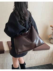 Side view of large dark brown polished leather tote bag showing generous capacity and fit