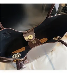 Detail of the magnetic snap closure on a dark brown leather tote bag with gold hardware