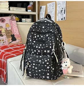 Primer plano de mochila negra ligera con estampado de estrellas y colgante de perro
