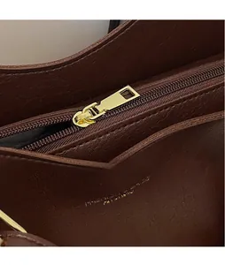Detail of polished gold hardware zipper and embossed logo on brown leather tote bag
