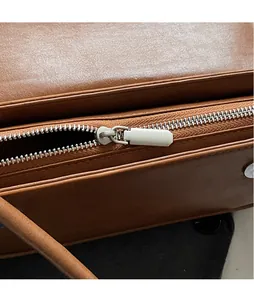 Macro shot of smooth silver zipper hardware and brown textured leather on handbag