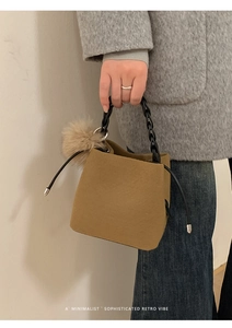 Detail of brown felt bucket bag with black chunky chain handle and pompom charm