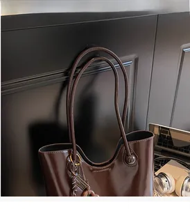 Close-up of durable dark brown leather straps and smooth finish of the bucket tote bag