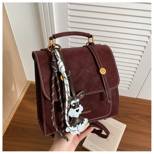 Detail of vintage burgundy leather backpack with schnauzer charm and gold hardware