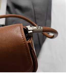 Close-up of silver metal hardware and rivet detail on brown leather shoulder bag