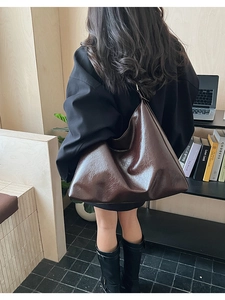Detail of a large vintage brown PU leather hobo shoulder bag shown on a model's back