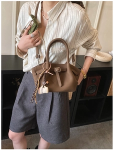Detail of dark brown pebble texture handbag with buckle strap and coffee cup charm
