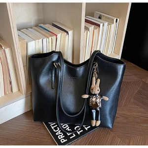 Detail of black PU tote bag with FASHION & BAGS text and a stylish bunny charm