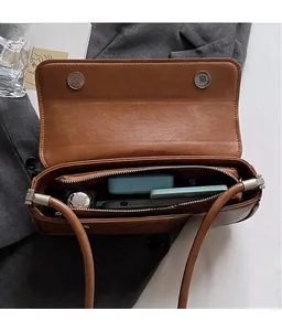 Interior view of brown faux leather shoulder bag showing organized compartments and zipper pocket