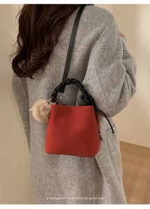 Detail of red twill woven handbag featuring black braided handle and brown fur pompom