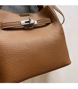Détail du grain de cuir litchi marron et du fermoir en métal argenté sur le sac seau