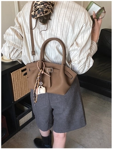 Detail of dark brown lychee leather bucket bag with coffee cup charm and scarf