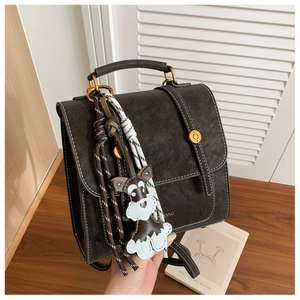 Detail of vintage dark brown backpack with golden hardware and schnauzer charm