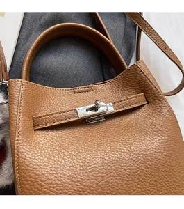 Gros plan sur un sac seau en cuir grainé marron avec fermoir pivotant en métal argenté