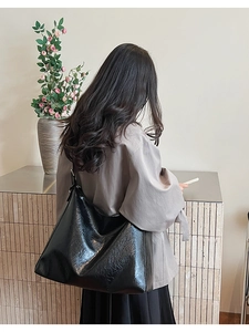 Grand sac hobo noir en similicuir plissé brillant porté à l'épaule par un mannequin