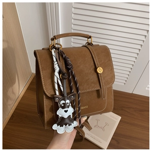 Detail of vintage brown leather bag featuring white contrast stitching and a dog-shaped charm