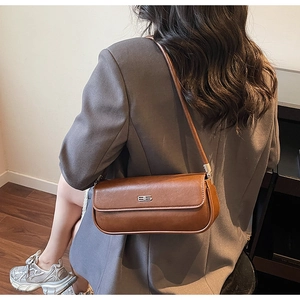 Brown faux leather baguette bag shown as a side view worn as a trendy underarm shoulder bag