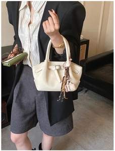 Detail of white lychee pattern bucket bag featuring a coffee rope pendant and leather strap