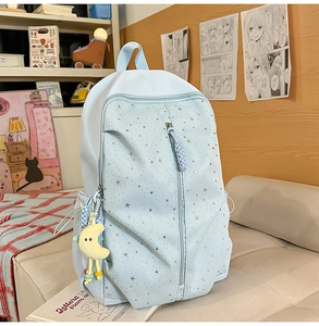 Detail of light blue student backpack with silver star patterns and moon plush charm