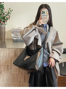 Détail d'un grand sac fourre-tout noir brillant avec texture en cuir poli et bandoulière