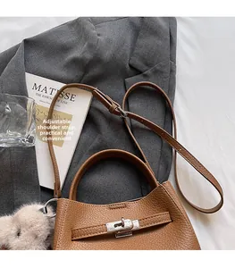 Vue détaillée du sac seau en cuir marron avec bandoulière réglable sur blazer gris
