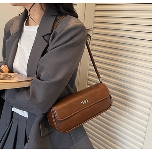 Brown vintage faux leather baguette bag with silver buckle worn over shoulder on a blazer