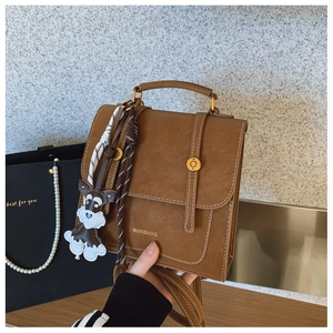 Detailed close-up of brown vintage backpack with white stitching and dog charm detail