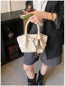 Close-up of beige lychee leather bucket bag with coffee charm and stylish decorative buckle