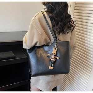 Detail of black faux leather tote bag showing texture and a cute bunny charm accessory