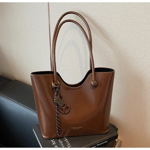 Close-up of retro brown tote bag with glossy leather texture and gold logo on books