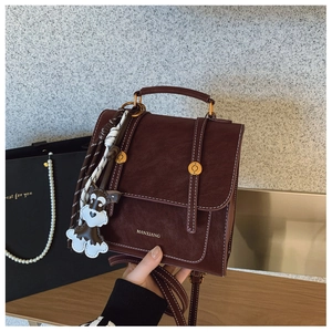 Detail of vintage brown leather handbag with contrast stitching and schnauzer charm