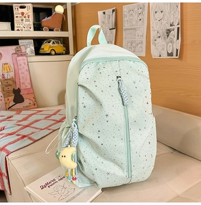 Detail of mint green backpack with silver star patterns and moon pendant accessory
