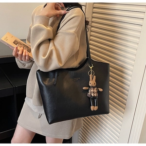 Detail of black tote bag with gold lettering and a stylish long-legged rabbit doll charm