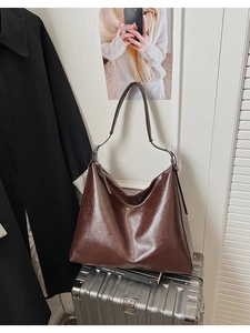 Détail d'un sac cabas en cuir ciré marron foncé avec texture brillante et bandoulière