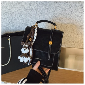 Detail view of black vintage leather handbag with white contrast stitching and gold lock
