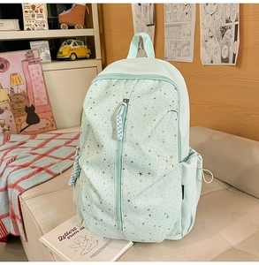 Detail of mint green backpack with star pattern and side drawstring pocket on sofa