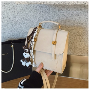 Detail of cream vintage crossbody bag with golden hardware and cute dog charm decoration