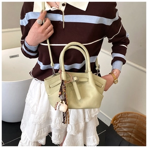 Close-up of light green bucket bag with coffee cup charm and leather texture detail