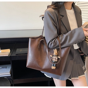 Detail of dark brown leather tote bag with a cute plush rabbit pendant charm