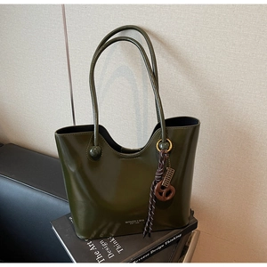 Olive green patent leather tote with wavy edge, branding detail and woven charm