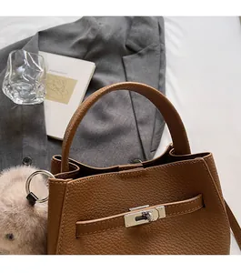Détail du sac seau en cuir grainé marron foncé avec fermoir argenté et pompon