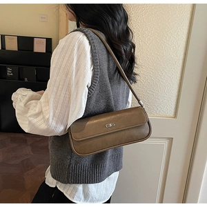 Close-up of a vintage dark brown baguette shoulder bag with silver logo and glossy finish