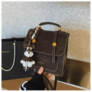 Detail of retro dark brown handbag with matte finish and cute puppy charm accessory