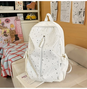 White canvas school backpack with star patterns and vertical zipper detail in cozy room