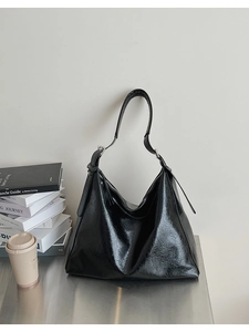 Détail du sac hobo en cuir huilé noir avec boucle argentée sur surface en acier