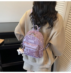 Detail eines lila bedruckten Rucksacks mit niedlichem Katzenanhänger und Nylon-Textur