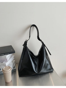 Détail du sac cabas en cuir plissé noir brillant avec boucle en métal argenté sur la bandoulière