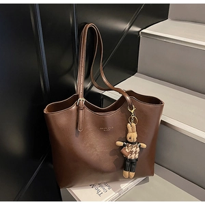 Detail of dark brown leather tote bag with fashion gold text and cute rabbit charm