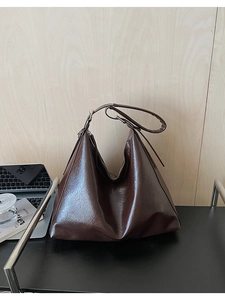 Texture détaillée d'un grand sac cabas marron foncé brillant avec surface plissée chic
