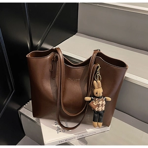 Detail of dark brown tote bag leather texture with gold lettering and cute bunny charm